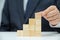 The hands of a male businessman who is stacking wooden blocks. Business concept