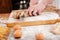 Hands of man baker cutting bread on wooden board