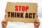 In the hands of a man is a cardboard sign with the inscription - Stop Think Act