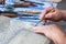 Hands of a man carving a picture of wood with a cutter