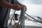 Hands of a man coiling up a rope, the sheet on a sailboat