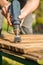 Hands man with electrical rotating brush metal disk sanding a piece of wood