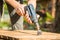 Hands man with electrical rotating brush metal disk sanding a piece of wood