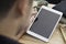 Hands of a man holding blank tablet device over a wooden workspace table