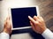 Hands of a man holding blank tablet device over workspace table