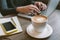 Hands of man on laptop with coffee and smartphone with notepad