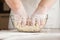 Hands of man preparing mound of bread dough on clear black table