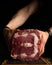 Hands of a man showing huge chunk of raw meat. Low key image, vertical orientation