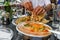 Hands of man tearing indian bread, rich table with meals