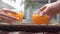 Hands of man and woman take glasses with orange juice coctail for drink.