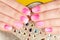 Hands with manicured nails with ombre gradient design in pink and white colors on crystals background