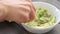Hands mashing avocado in bowl with a fork. Table top view footage. Healthy food cooking.