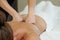 Hands of masseuse pressing punches against back of young woman
