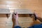 hands of a master carpenter attach a wooden shelf to the wall. Production of handmade furniture to order