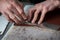 Hands of master cutting with a knife pattern from genuine leather closeup