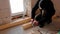 Hands of master twist washer with nut onto a threaded steel stud into concrete floor of rough floor for installation of wooden