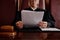 Hands of mature female impartial judge holding juridical documents over desk