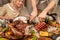 Hands of mature man cutting piece of roasted turkey on festive table by dinner