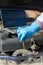 Hands of a mechanic with gloves doing a check up of a car`s diesel engine with tools and wrenches and laptop