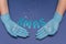 Hands in medical gloves on blue background. Glitter little stars in hands. Inscription XMAS. Christmas and New Year card