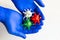 Hands in medical gloves holds virus models in white, red and green colors.