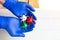 Hands in medical gloves holds virus models in white, red and green colors.