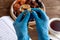 Hands in medical gloves with prayer beads on background of Cup of tea, plates of dried fruit, Koran, iftar concept, Ramadan in