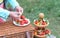 The hands of a middle-aged Caucasian woman are preparing a fruit barbecue from strawberries, grapes and cheese