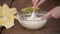 Hands Mixing Batter with a Spatula in a Glass Bowl