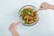 Hands mixing delicious vegetable salad on a glass plate