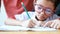 Hands of mother and grandmother family teaching Asian little girl in Thai kindergarten student uniform to doing homework on wood t