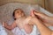 Hands of mother or masseuse massaging foot of infant baby. Closeup of relaxed little infant receiving feet reflexology at home