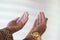 Hands of muslim people praying with mosque interior background.