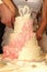 Hands of the newlyweds cut a wedding cake decorated with swans