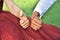 Hands of newlyweds with like symbol from fingers, bride in red on green grass