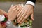 Hands of the newlyweds with rings on their fingers, near a bouquet of roses, the bride and groom hold hands