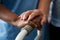 Hands of nurse and senior woman holding walker in nursing home
