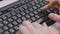Hands of office worker pressing buttons on keyboard and holding pen