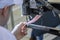 Hands of an old and experienced worker in the handmade shoe industry, performing sewing tasks on a piece of genuine leather, on a