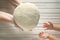 The hands of an old woman transmit bread dough to the small hands of a girl. The intergenerational connection.