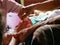 Hands of old woman waving a white string  Sai Sin  around her granddaughter hands - Thai traditional blessing from an elder one