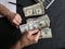 hands of an older man counting american dollars banknotes