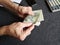 hands of an older man counting american dollars banknotes