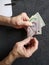 hands of an older man counting singaporean banknotes