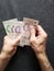 hands of an older man counting singaporean banknotes