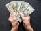 hands of an older man holding american dollars banknotes