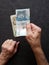 hands of an older man holding colombian banknotes