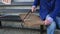 Hands of older man working cutting plank with wood handsaw outside on the ground on picnic