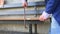 Hands of older man working cutting plank with wood handsaw outside on the ground on picnic