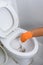 Hands in Orange gloves cleaning WC, Toilet, lavatory using brush